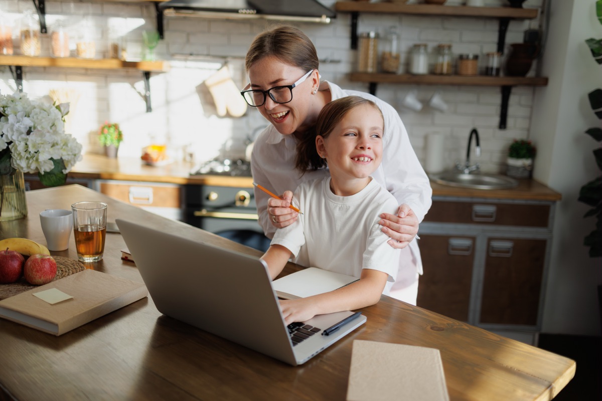 A parent and child at a laptop at the kitchen table